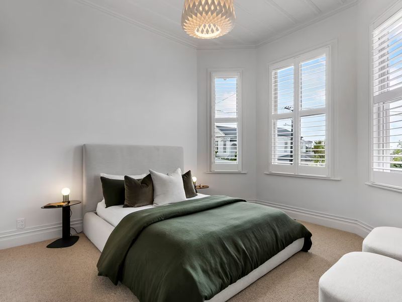 Corner bedroom with tall windows, wood flooring and a fringed throw