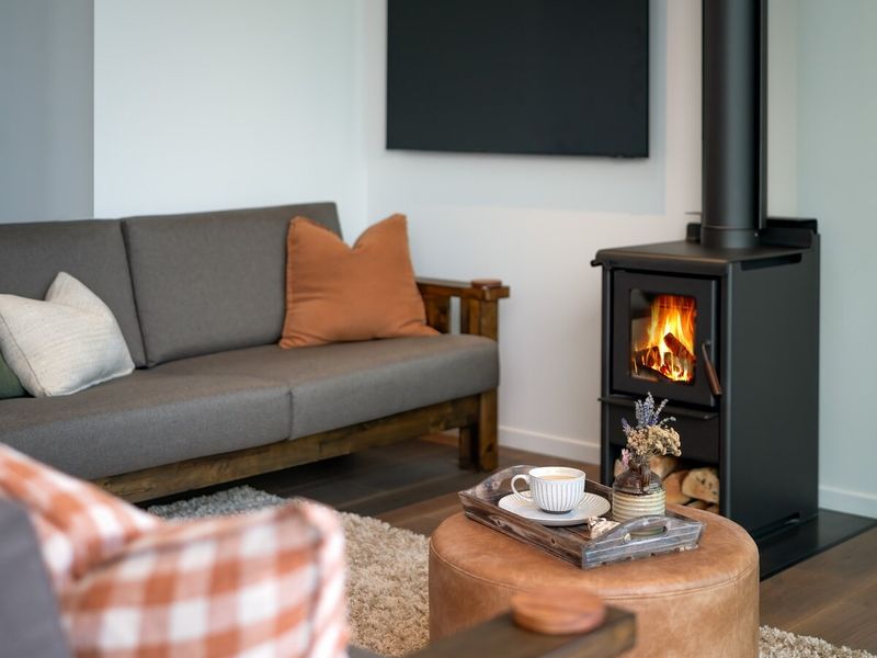 Living room with a wood burner, leather ottoman and layered textures around the fireplace