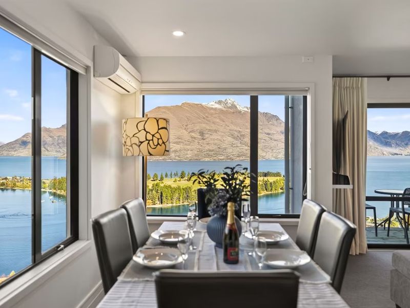 Dining table set for two with lake and mountain views through floor-to-ceiling windows