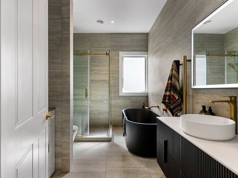 Bathroom with a freestanding black tub, brass fixtures and a walk-in shower