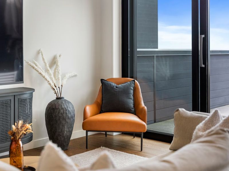 Corner reading nook with a leather armchair and dried pampas grass beside a sliding glass door