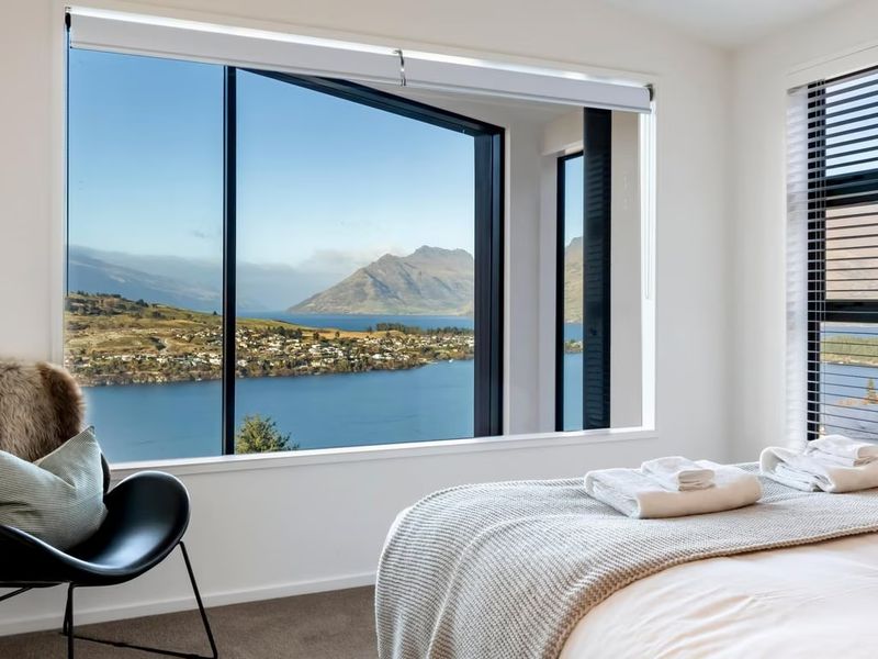 Bedroom with a picture window framing the lake and mountains, dressed with folded towels