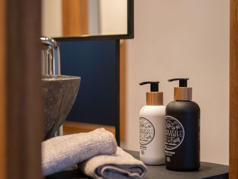 Bathroom vanity detail with stone basin, folded towels and eco-friendly amenities