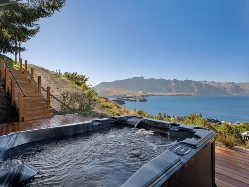 Outdoor hot tub on a deck with sweeping lake and mountain views
